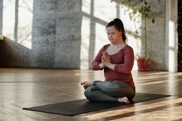 Inclusive Approach to Authentic Buyer Personas: woman with Down Syndrome sitting on yoga mat meditating